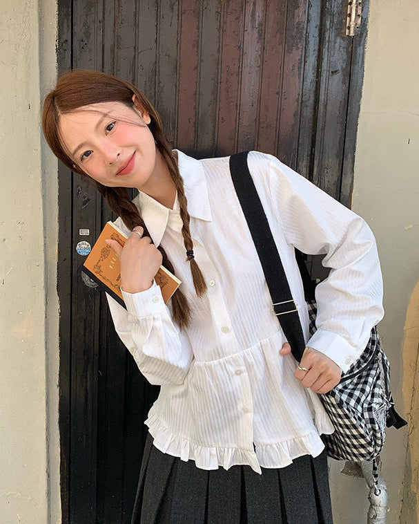 Woman in a white blouse and black skirt standing in front of a wooden door.
